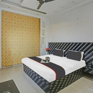 A bedroom with a patterned wallpaper, a bed with a black and white headboard, and a ceiling fan.