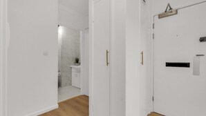 A hallway with white walls and wooden flooring leading to a bathroom with a marble shower and toilet. - Queens Quay Mansion House Flat (London)