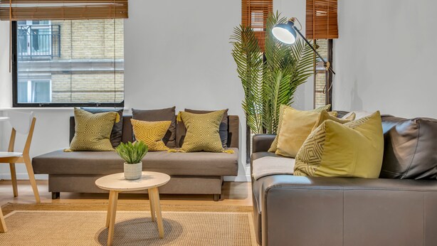 A modern living room with a sofa, a coffee table, and a potted plant. - Queens Quay Mansion House Flat (London)