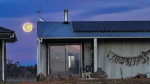Ein modernes Gebäude mit einer großen Glastür, Solaranlagen auf dem Dach und einem Metallzaun mit Hirschgeweihen.