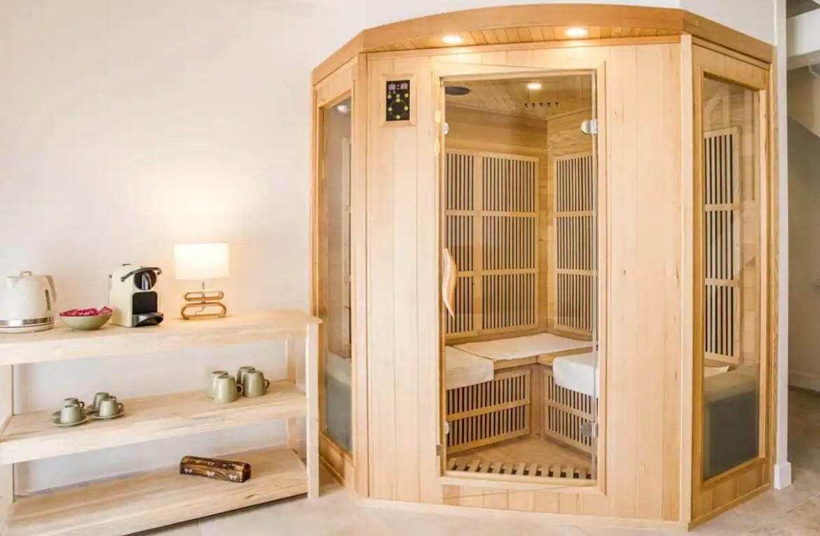 A wooden sauna with a control panel, a shelf with tea sets, and a mirror.