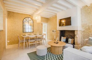 A cozy living room with a fireplace, a dining area with a round table, and a large window with a decorative arch. - Detached house with jacuzzi and sauna in Normandy   (Ranville)