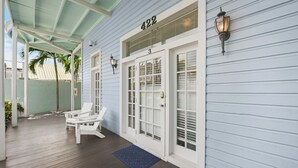 A covered porch with white chairs, a blue mat, and a house number 422.