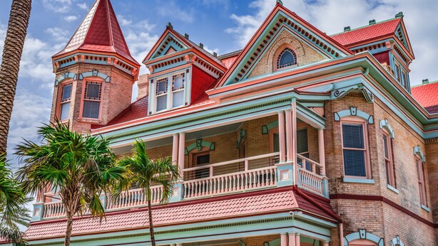 A Victorian-style building with a prominent tower, multiple balconies, and a red-tiled roof.