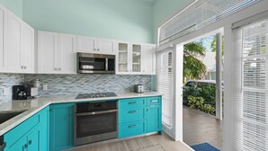 A modern kitchen with teal cabinets, a microwave, and a coffee maker.
