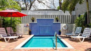 A rectangular pool with a blue tiled wall, surrounded by lounge chairs and a red umbrella. - Old Town Key West suite w/ pool & pet-friendly (Key West)
