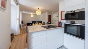 A modern kitchen with white cabinetry, a built-in oven, and pendant lighting. - Grande Anita - City center - Private parking (Barcelonnette)