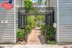 A gated entrance with a number sign, a brick pathway, and potted plants. - Orchid Suite on Center St - 1/2 block from Duval Sleeps 4 (Key West)