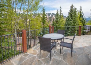 An outdoor patio with a stone floor, a round table, and four wicker chairs. - Private House with Hot Tub in Vail, 796APP (Vail)