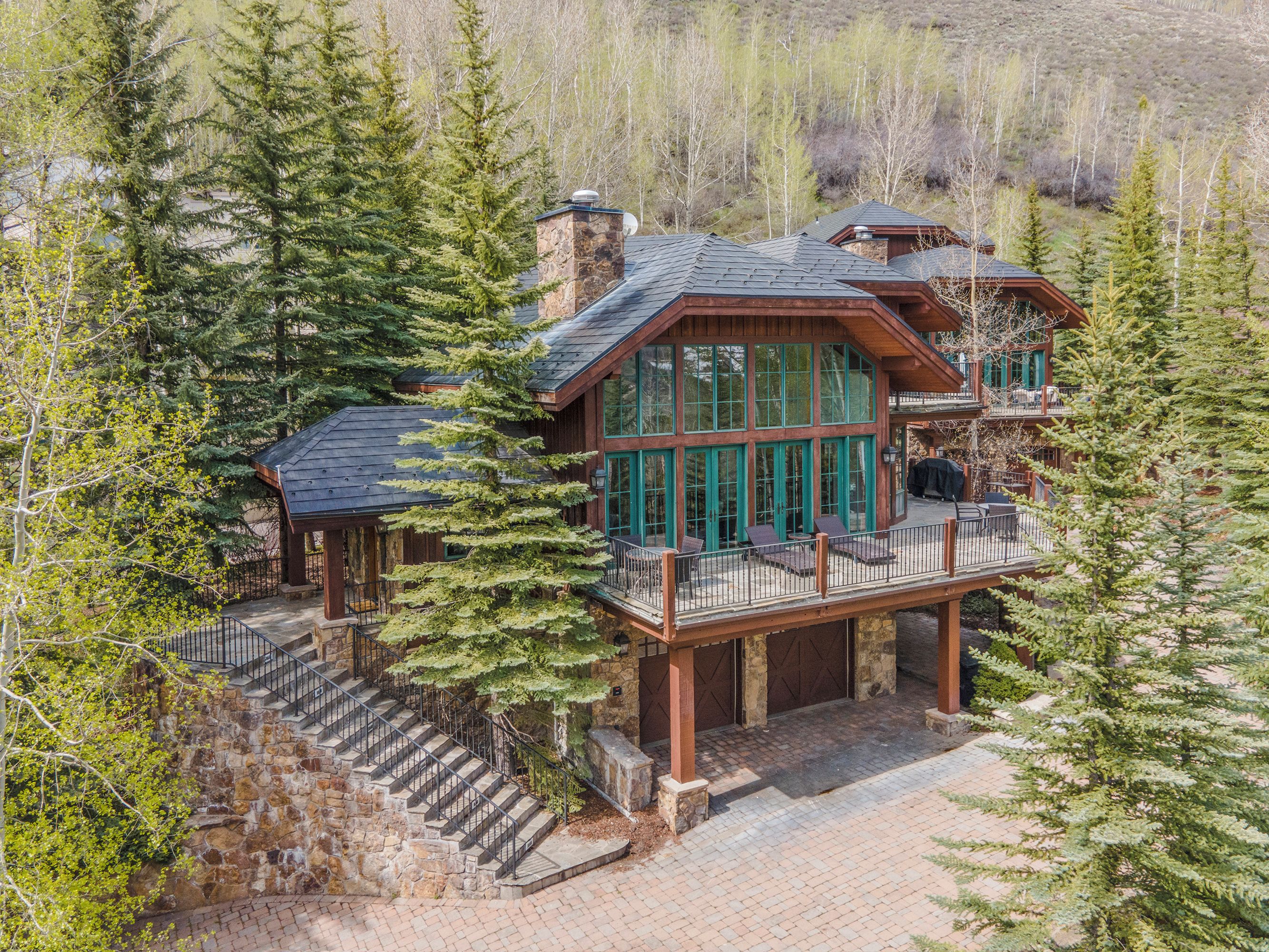 A large wooden cabin with a deck, surrounded by trees.