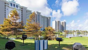 A grassy area with mailboxes and a pond, surrounded by tall buildings. - Majestic Sun #412A | Beach Views & Fun On-Site Amenities! (Miramar Beach)