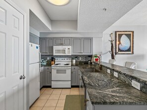 Une cuisine moderne avec des meubles gris, une cuisinière blanche et un plan de travail en granit.