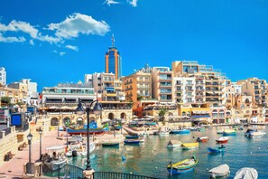 Un paisaje urbano costero con un puerto deportivo, edificios y una torre destacada.