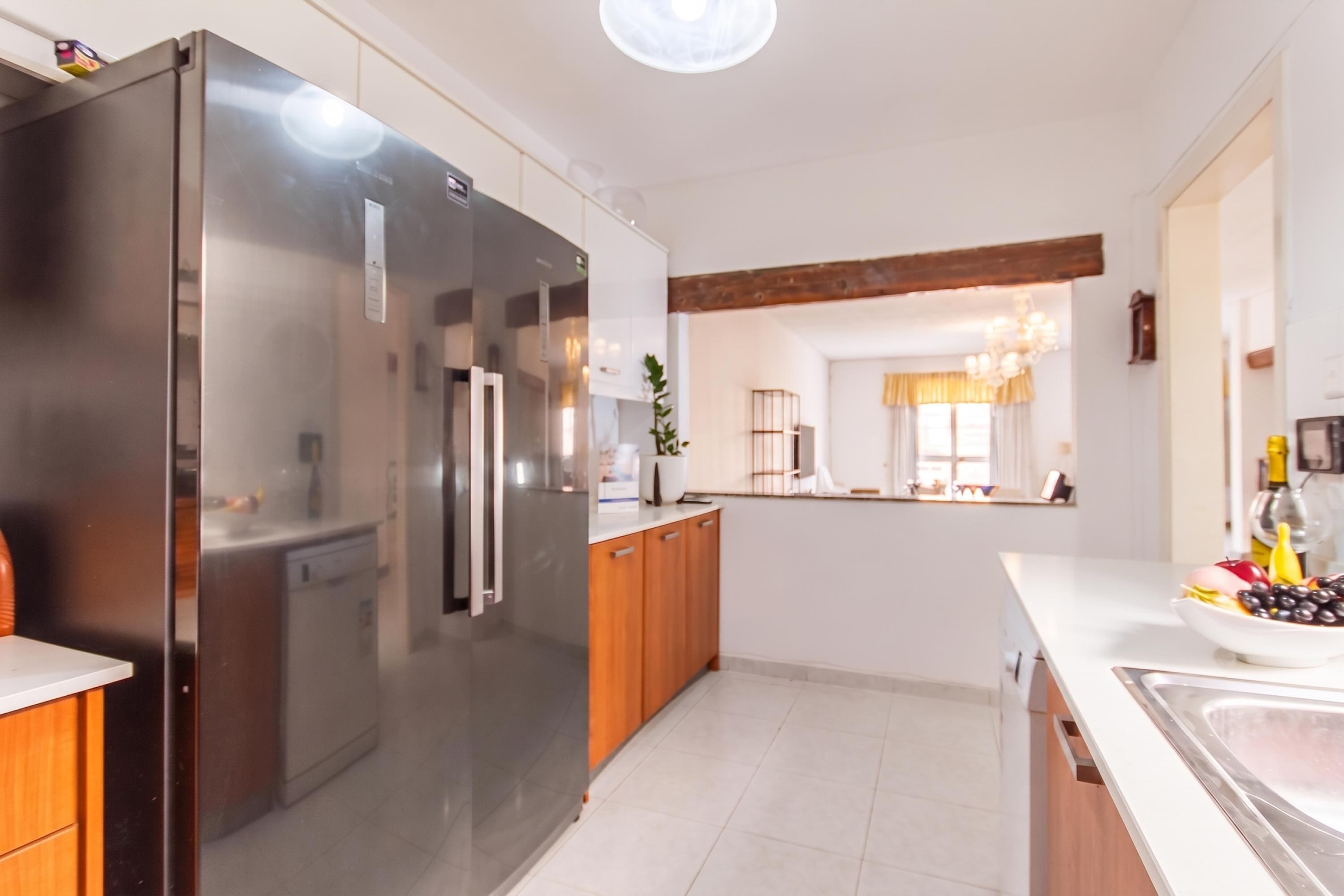 A modern kitchen with a stainless steel refrigerator, wooden cabinets, and a white countertop.