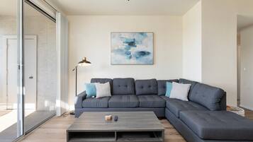 A modern living room with a sectional sofa, a coffee table, and a large abstract painting on the wall.