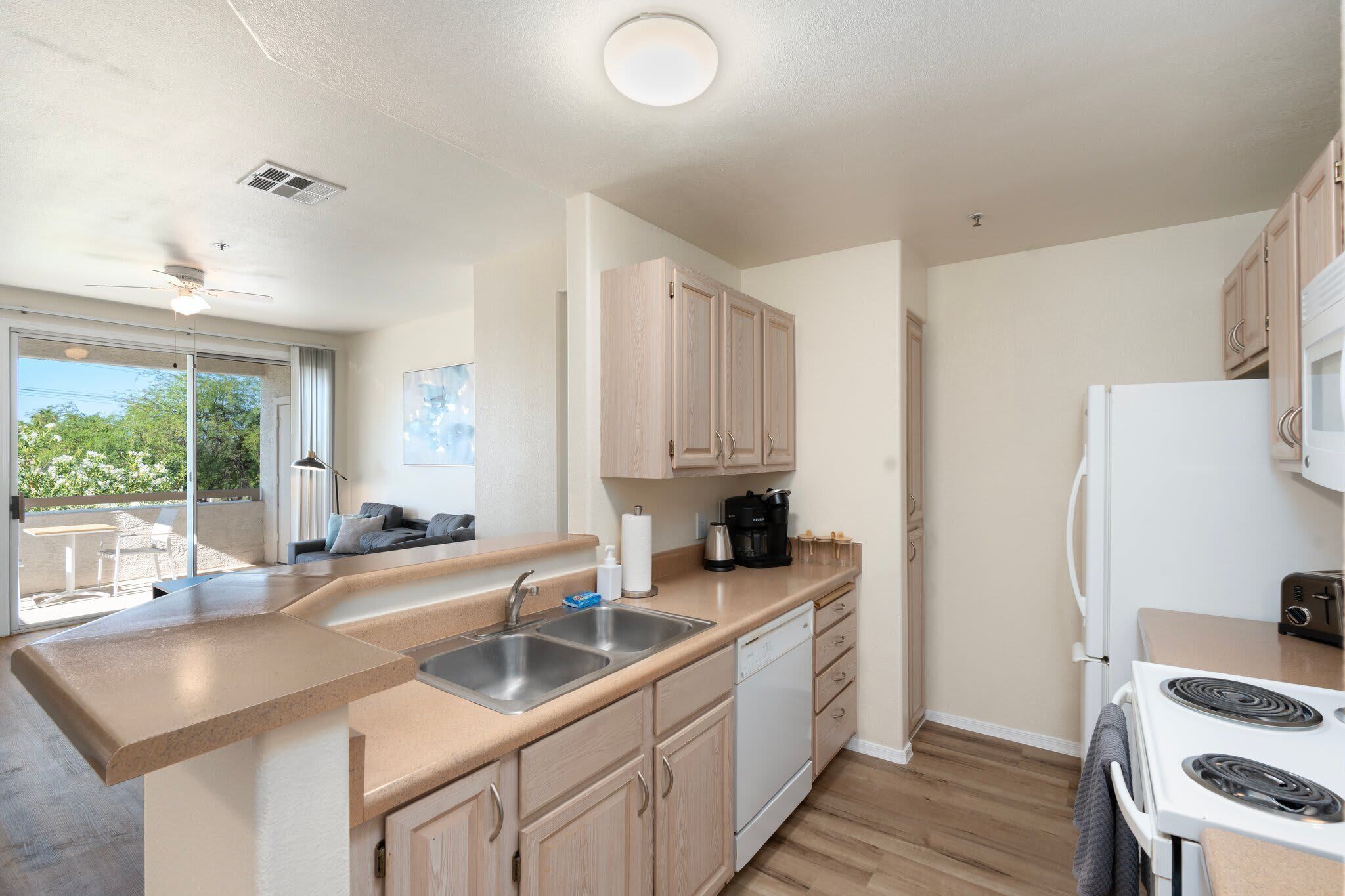 Una cocina moderna con una isla grande, pileta de acero inoxidable y muebles de madera.