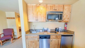 A compact kitchen with wooden cabinets, a microwave, a sink, a coffee maker, and a dishwasher. - Grand Lodge Studio 153 — 5-Min Walk to Ski Lifts | Pool, Hot Tub, Pet-Friendly (Crested Butte)