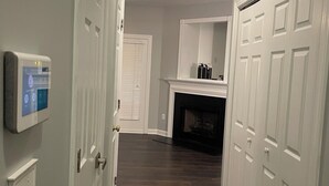 A hallway with a thermostat, a fireplace, and a set of white doors. - Charming 2-bedroom townhome in wonderful Raleigh with WiFi, AC (Raleigh)