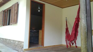 Ein Zimmer mit Holzboden, einem zur benachbarten Kammer führenden Durchgang und einer roten Hängematte an der Wand.