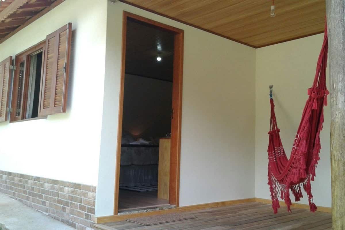 A room with a wooden ceiling, a doorway leading to another room, and a red hammock hanging on the wall.