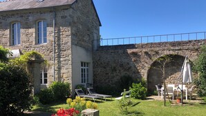 A stone building with a garden, outdoor seating, and a stone bridge.