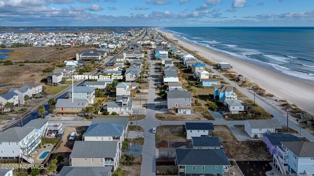 Vista aérea de una zona residencial costera con casas, una playa y una carretera con la indicación '1402 N New River Drive'.