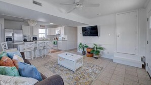 Una sala de estar moderna con un sofá blanco, una mesa de centro y un televisor montado en la pared.