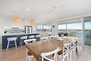 Une cuisine moderne avec un coin bar, une table à manger avec des chaises et une vue sur un plan d’eau.