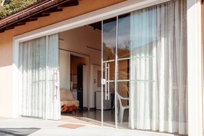 A modern house with large sliding glass doors leading to a living area with a sofa and a dining table. - Recanto Lago Negro - Rancho Queimado (Rancho Queimado)