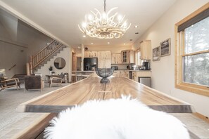 A spacious living room with a wooden coffee table, a chandelier, and a view of the kitchen and dining area. - Grand Chalet At Grand Lake 4 Bedroom Cabin by RedAwning (Grand Lake)