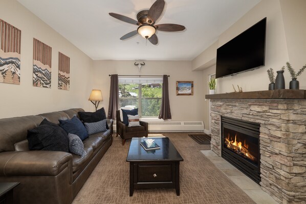 Relax in this stylish living room with a leather sofa, stone fireplace, and flat-screen TV.