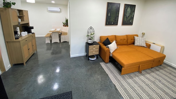A modern living room with a sofa, coffee table, and a dining area with a table and chairs.