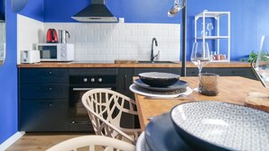 Una cocina moderna con pared azul, azulejos blancos, encimera de madera, estufa negra y una silla blanca.