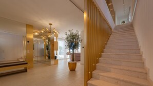 Um interior moderno com escadas, uma grande planta em vaso e um banco.