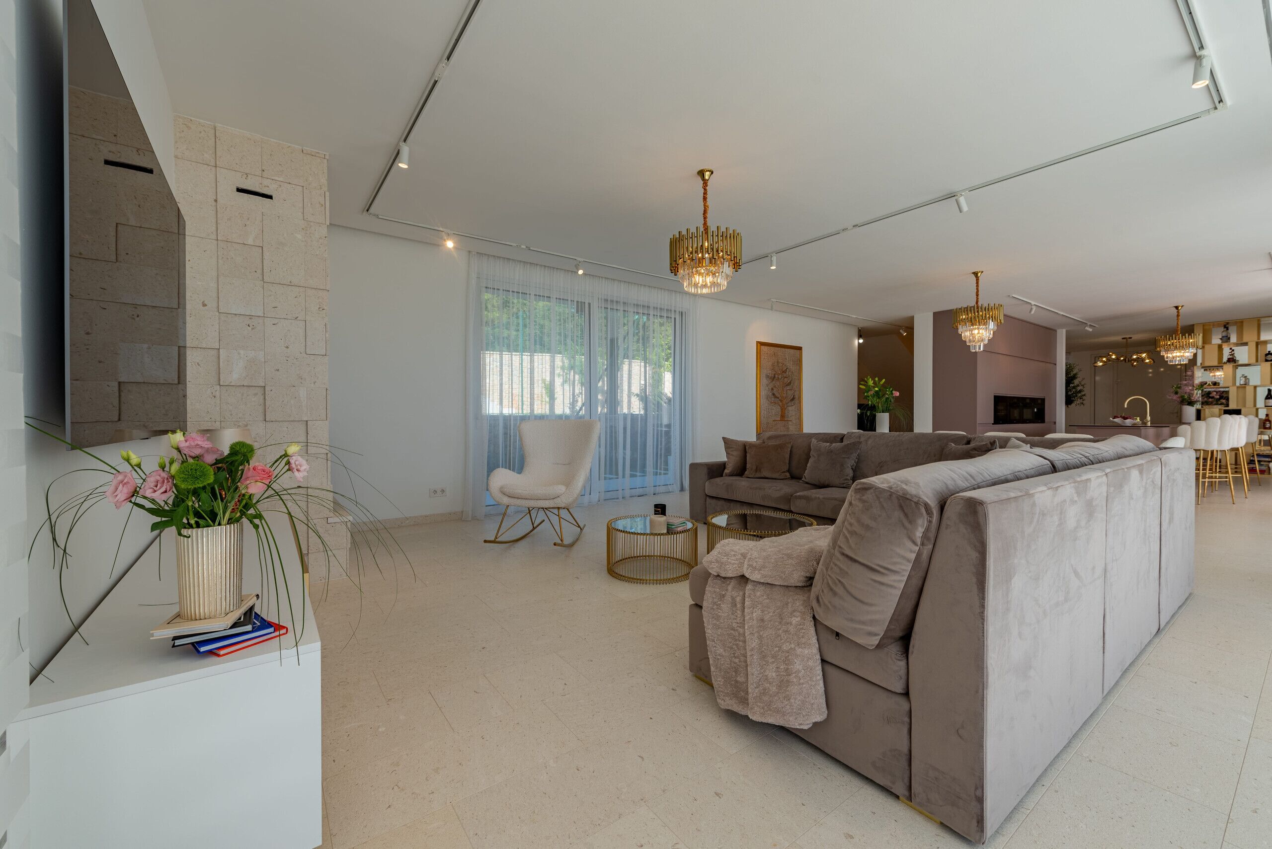 A modern living room with a large sectional sofa, a white armchair, and a dining area in the background.