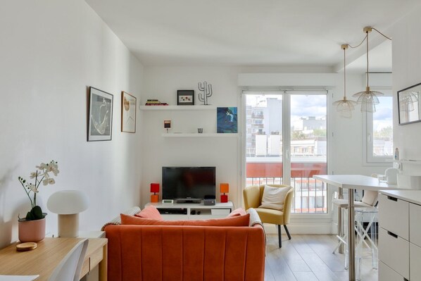 Un salon moderne avec un canapé, un téléviseur et un coin repas.
