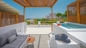 Eine Dachterrasse mit einer Holz-Pergola, einem weißen Sofa, einem kleinen runden Tisch mit einer Flasche und Gläsern sowie einem Whirlpool.