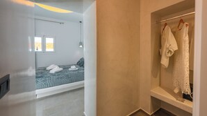 Ein modernes Schlafzimmer mit einem Bett, einem Fenster und einem begehbaren Kleiderschrank mit aufgehängter Kleidung.
