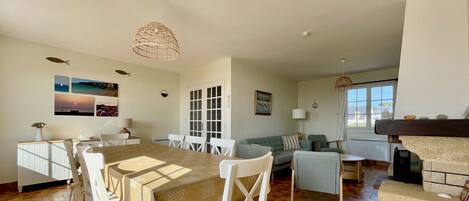 A spacious living area with a dining table, chairs, a sofa, and a fireplace.