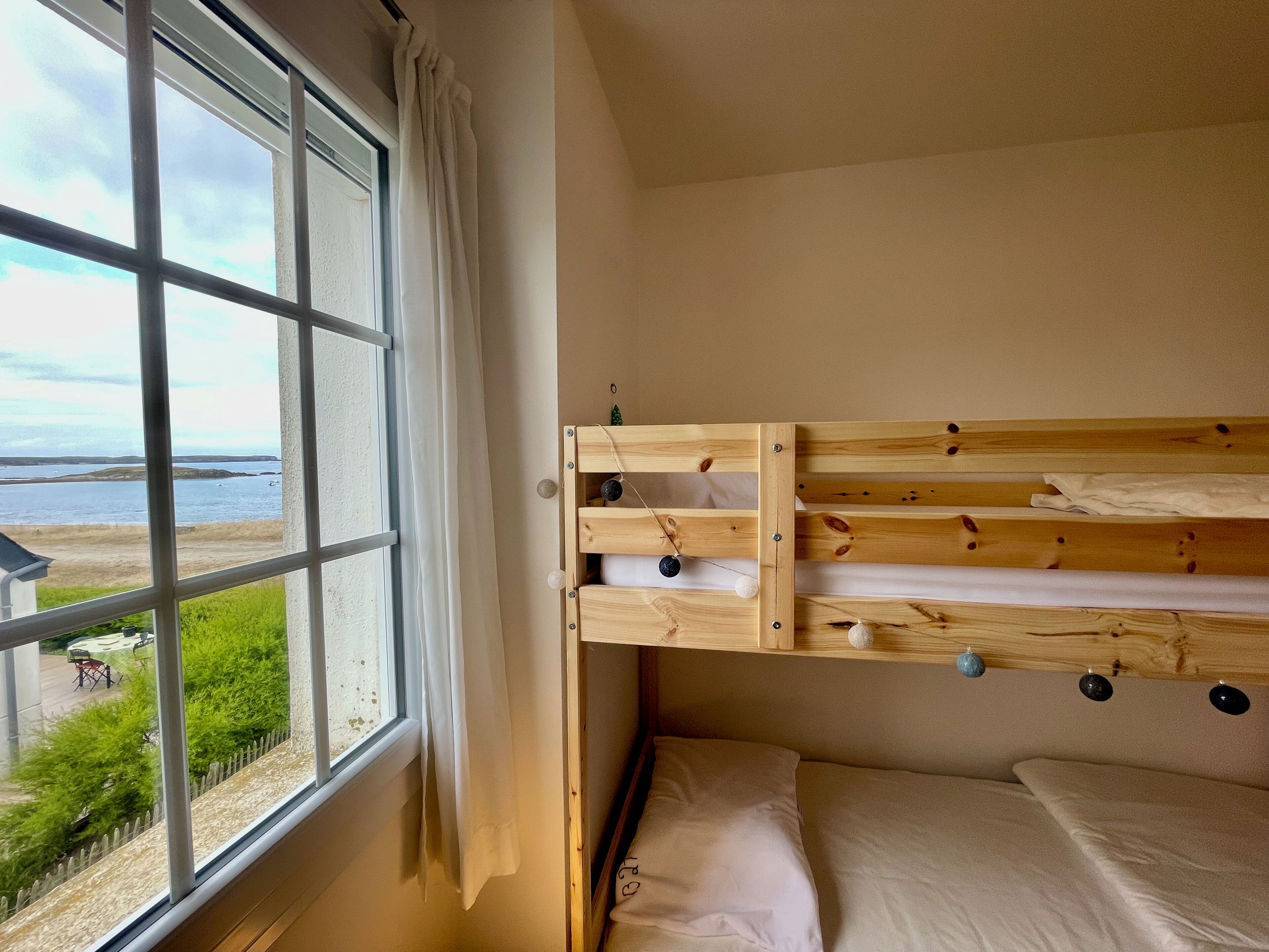 Una cama individual con vista al mar a través de una ventana.