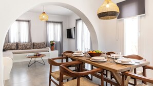 Comedor con una mesa de madera dispuesta para cuatro personas, rodeado de sillas de mimbre.