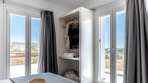 Un dormitorio con cama, sombrero, armario y vistas al exterior.