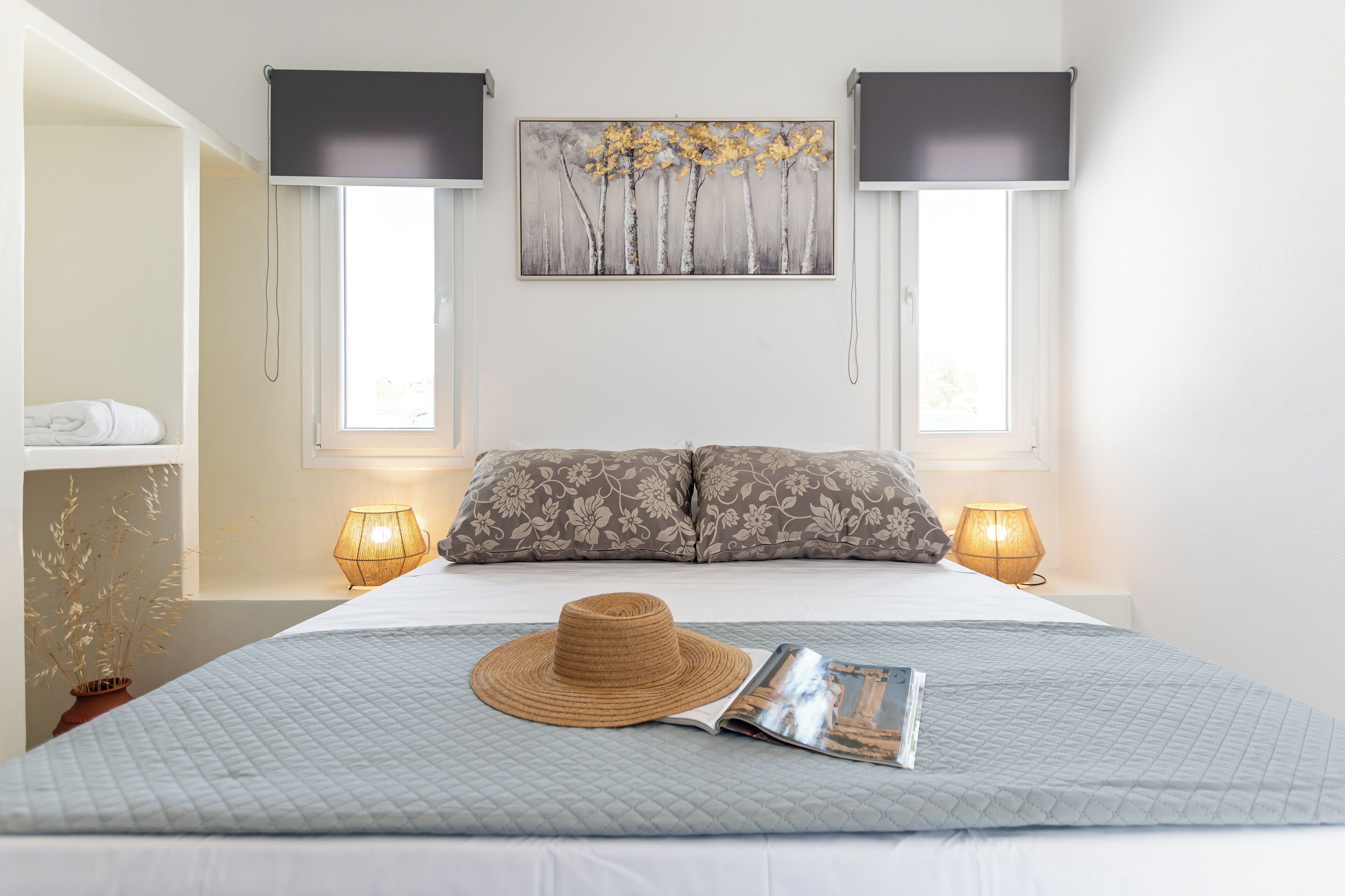 Une chambre à coucher avec un lit, deux lampes de chevet, un tableau accroché au mur et une fenêtre.