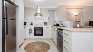 Eine moderne Küche mit weißen Schränken, einem Edelstahl-Kühlschrank, einem Gasherd und einem eingebauten Backofen.
