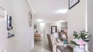 Eine moderne Küche mit weißen Schränken, einem Kühlschrank und einem Essbereich mit Tisch und Stühlen.