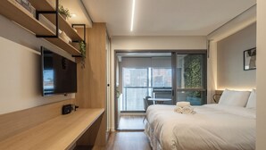 A modern hotel room with a bed, a TV, a desk, and a balcony with a view. - 360 Ambience Vila Mariana (São Paulo)