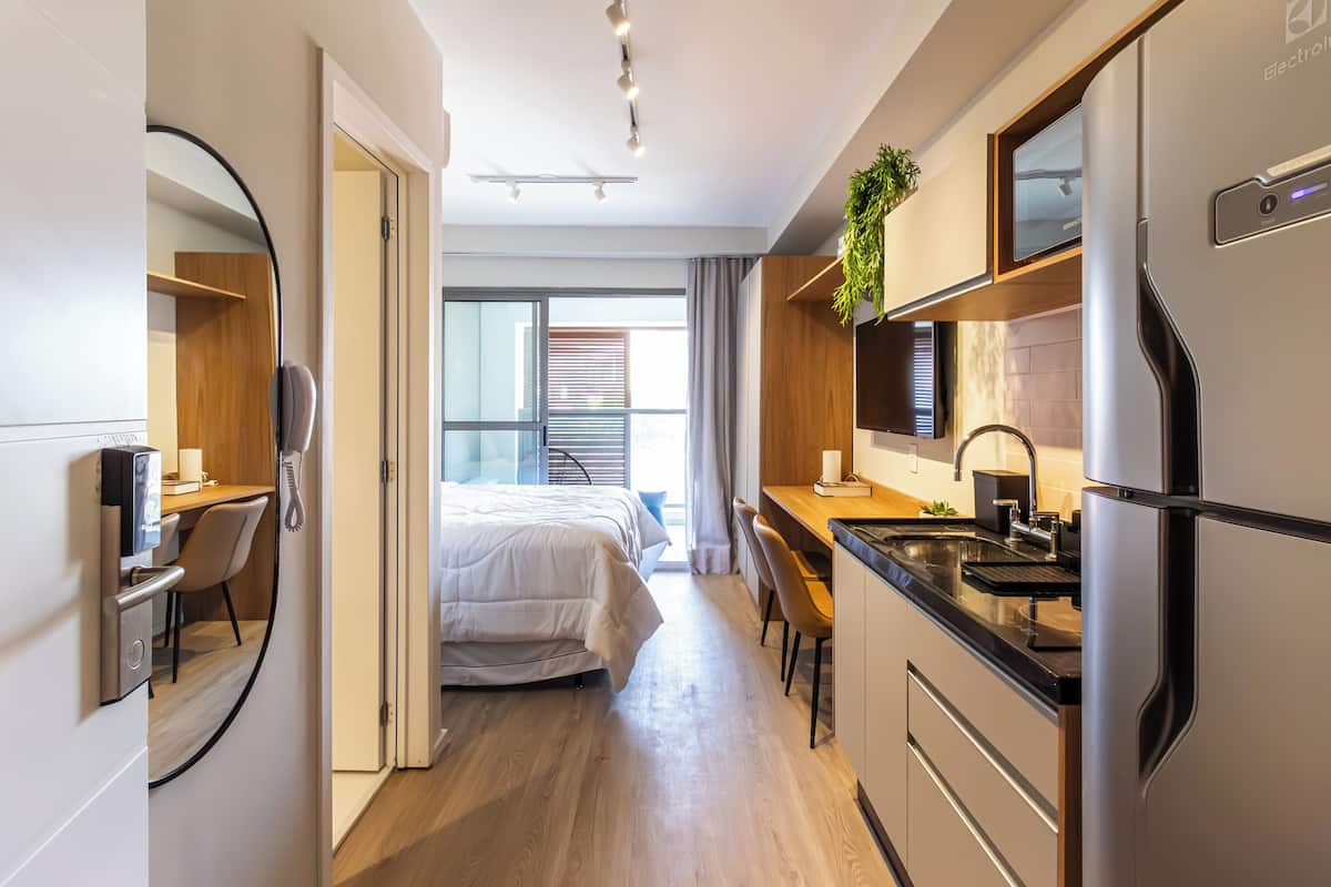 Une chambre d’hôtel moderne équipée d’un lit, d’un bureau, d’un lavabo et d’un réfrigérateur.