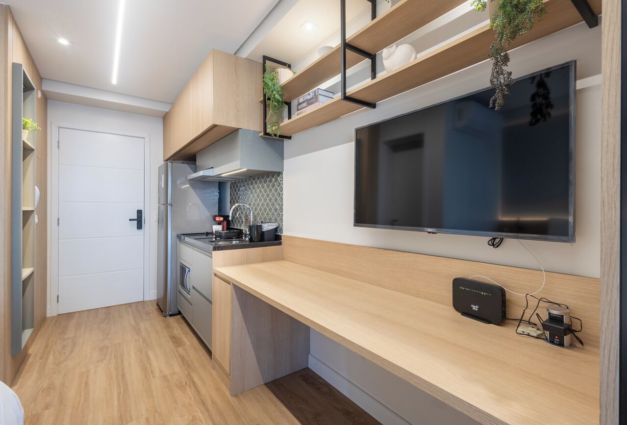 Una cucina moderna con forno integrato, microonde e macchina del caffè. C'è un piano di lavoro in legno e un televisore montato a parete.