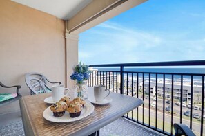 A balcony with a table set for breakfast, including muffins and a vase with flowers, overlooking a coastal view. - 9th floor Ocean view 3 BR condo| Short walk to beach| Resort Access|Free Parking (North Myrtle Beach)
