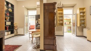 Ein geräumiges Wohnzimmer mit einer großen Holzsäule, einem Essbereich mit Tisch und Stühlen sowie einer durch eine offene Tür einsehbaren Küche.